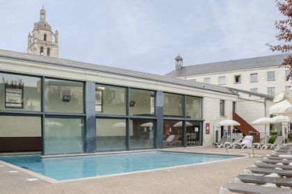 La piscine semi-couverte de 100m² et sa terrasse avec transats et parasols